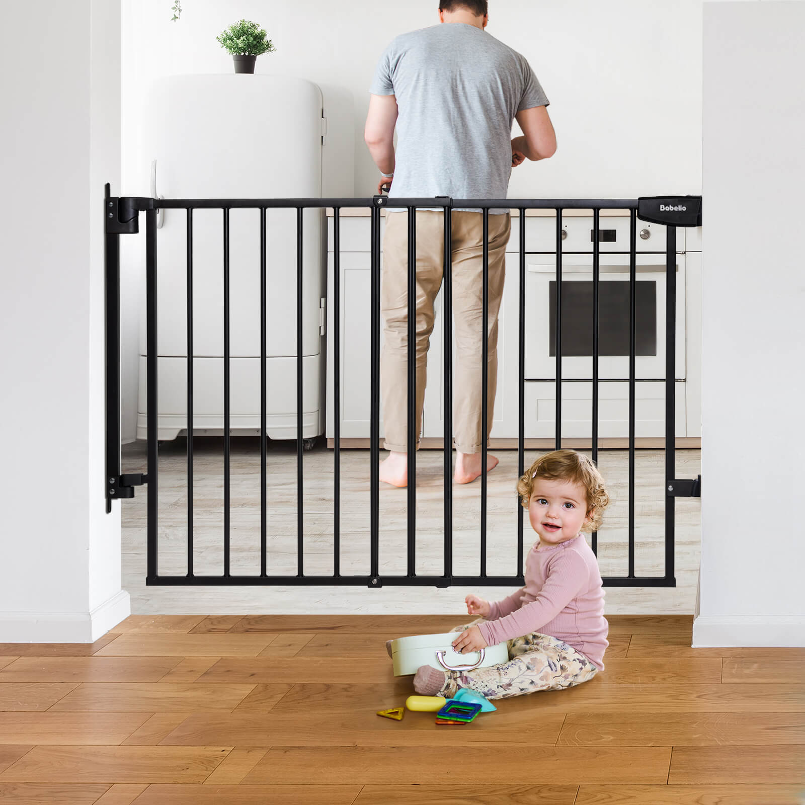 Adjustable baby gate installed at the top of the stairs with a small child sitting on the floor beside it, playing with toys.