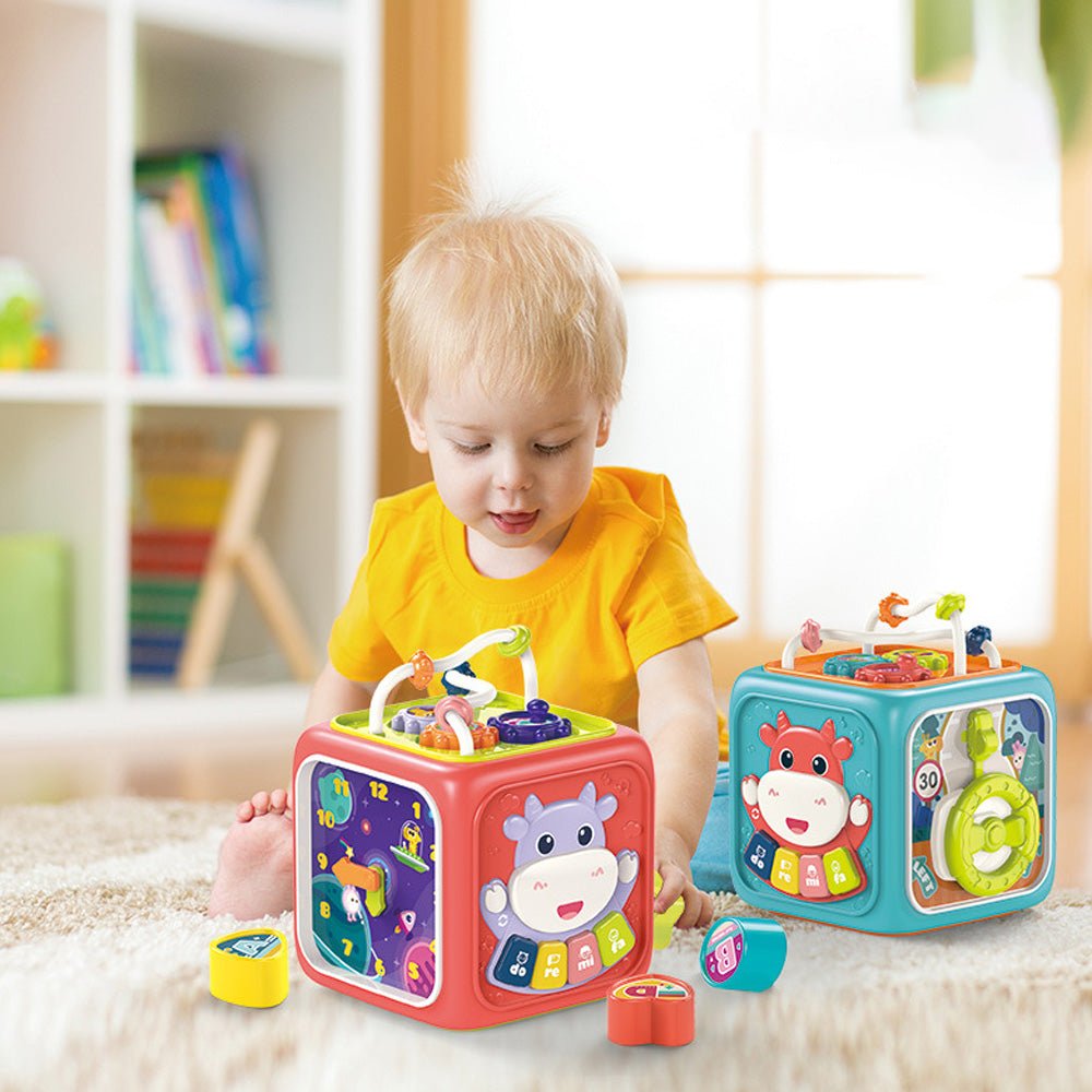 Babelio baby playing with colorful activity cubes on a nursery rug, educational toys visible