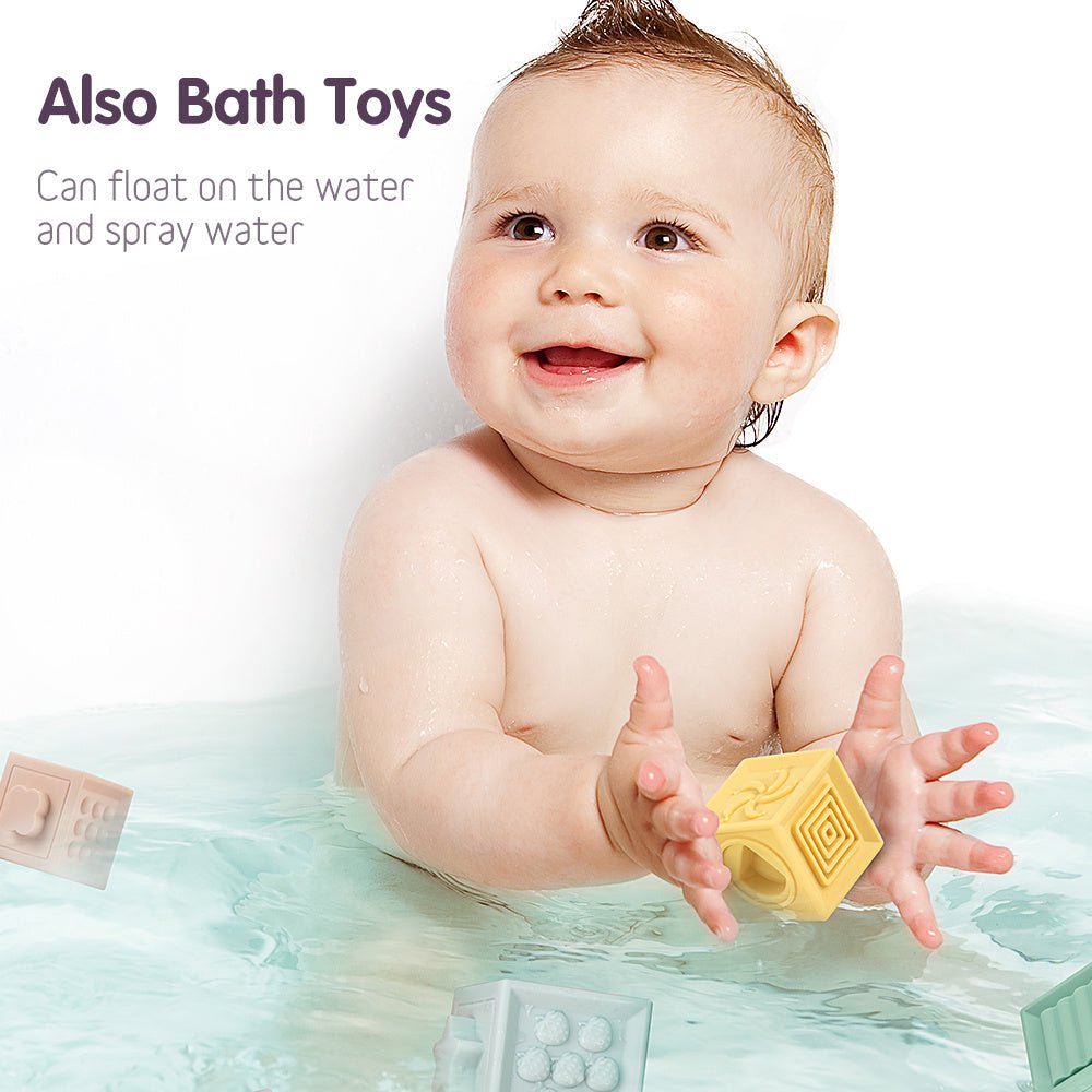 Smiling baby playing with Babelio bath toys in a bathtub holding a yellow floating block.