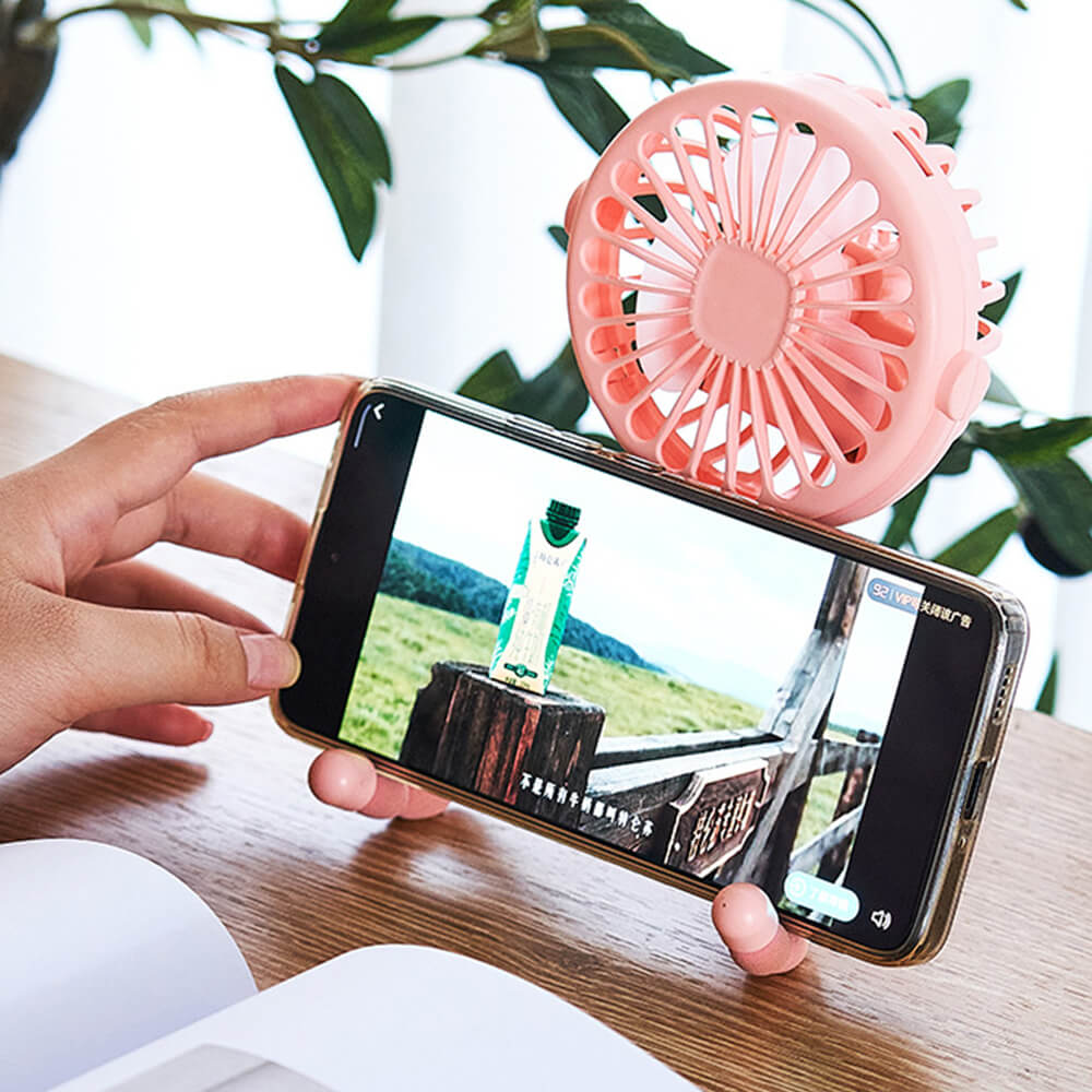 Babelio portable pink mini fan with flexible legs holding a smartphone on a wooden desk