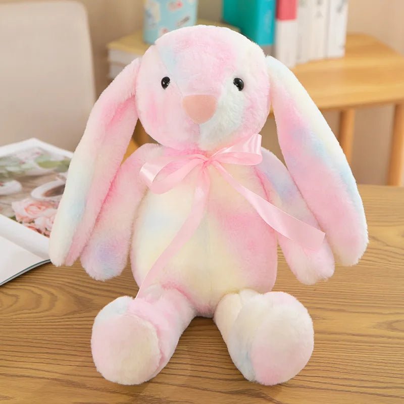 Babelio pastel plush bunny toy with pink ribbon on a wooden table in a nursery setting