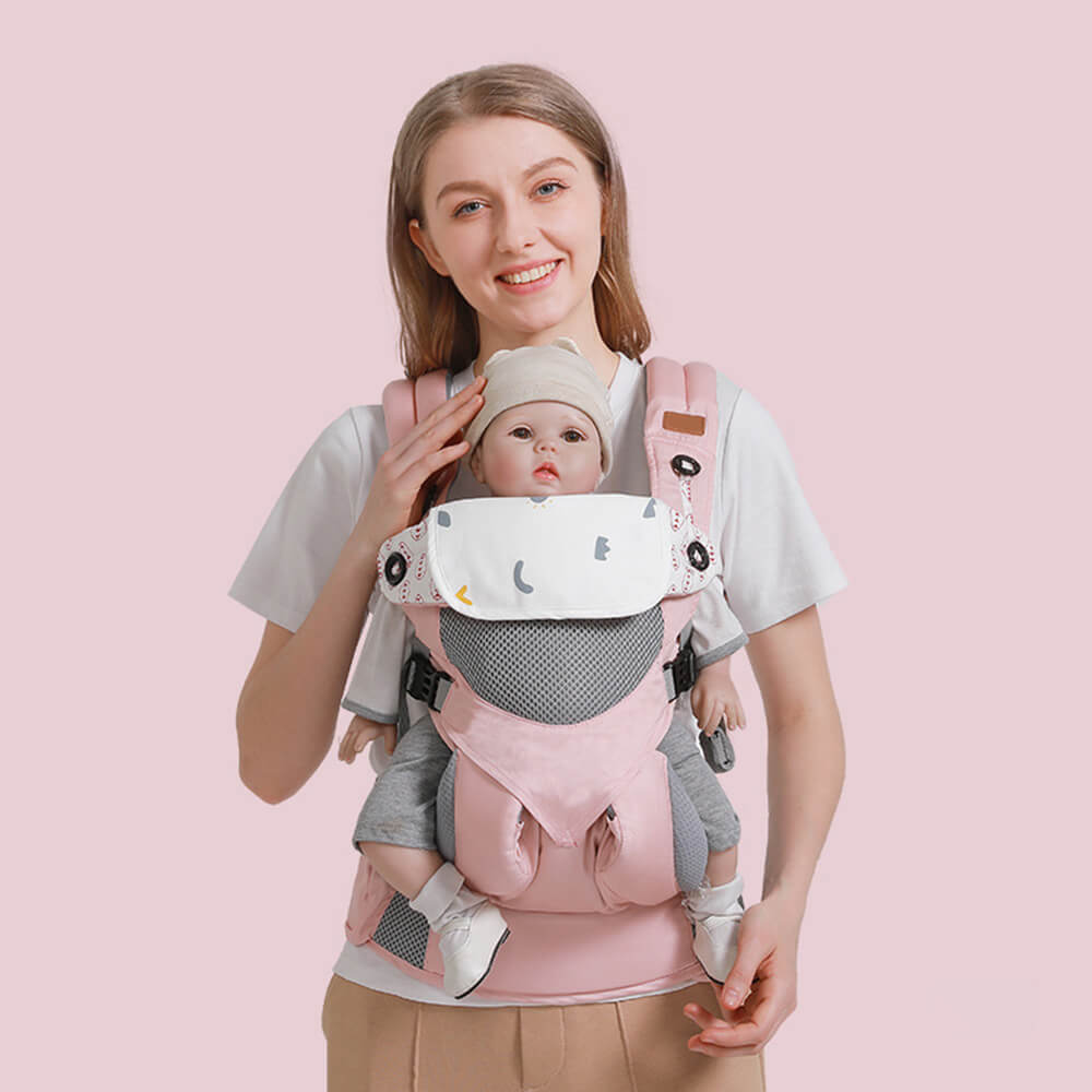 Babelio ergonomic pink baby carrier with hip seat, worn by woman, baby in front, studio background