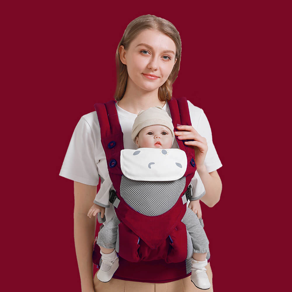 Babelio baby carrier in red with ergonomic hip seat, worn by parent in indoor setting
