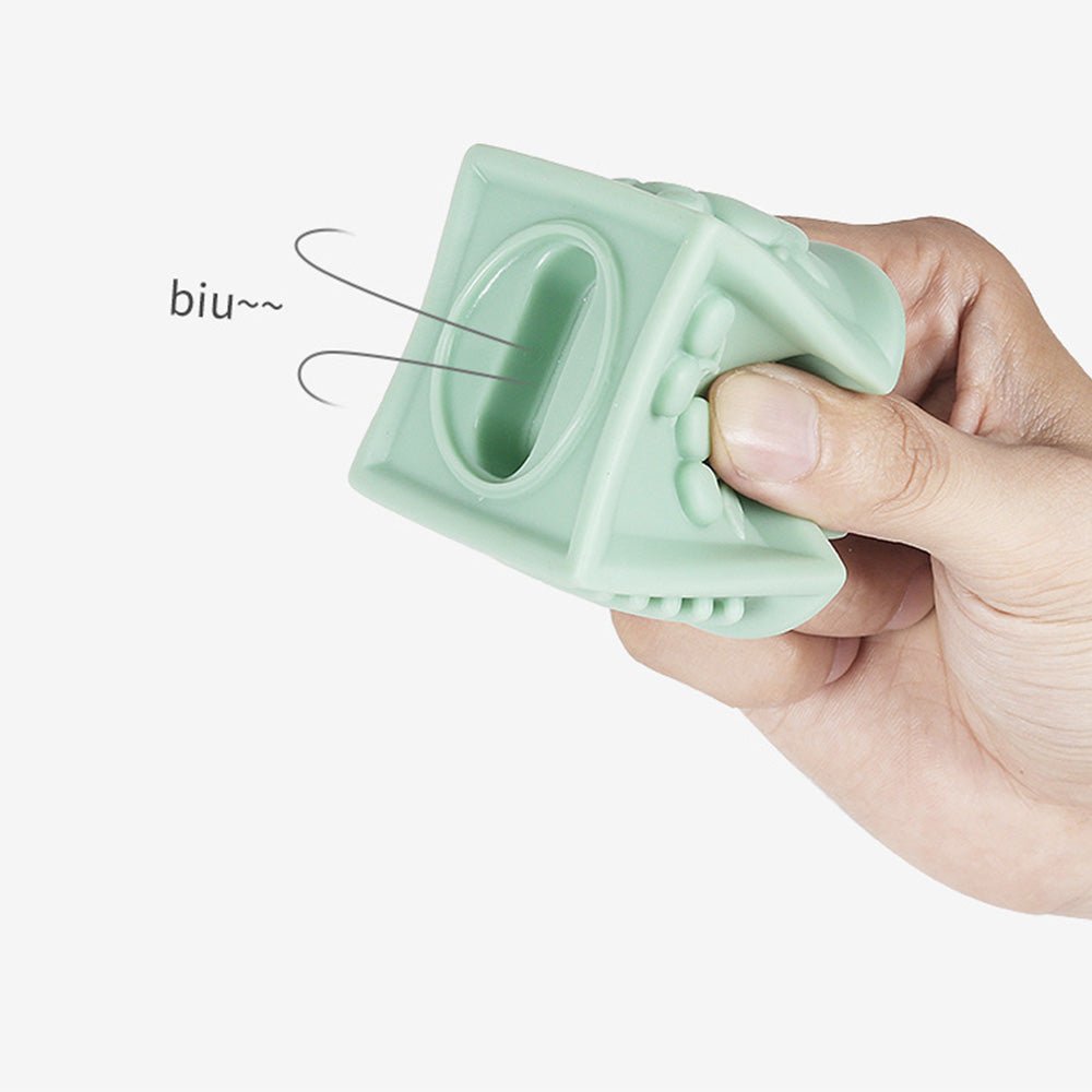 Hand squeezing Babelio mint green silicone baby teether toy on white background