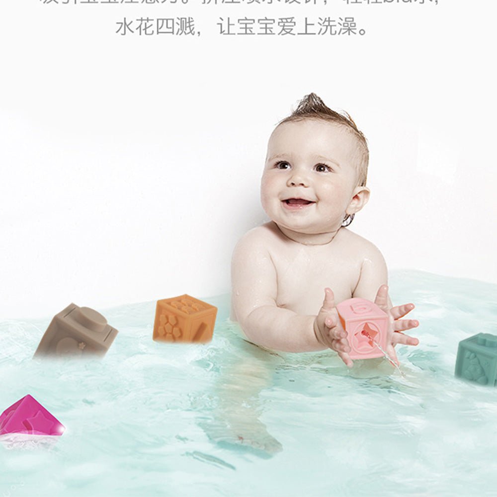 Babelio baby playing with colorful bath toys in a bathtub, smiling and splashing water.
