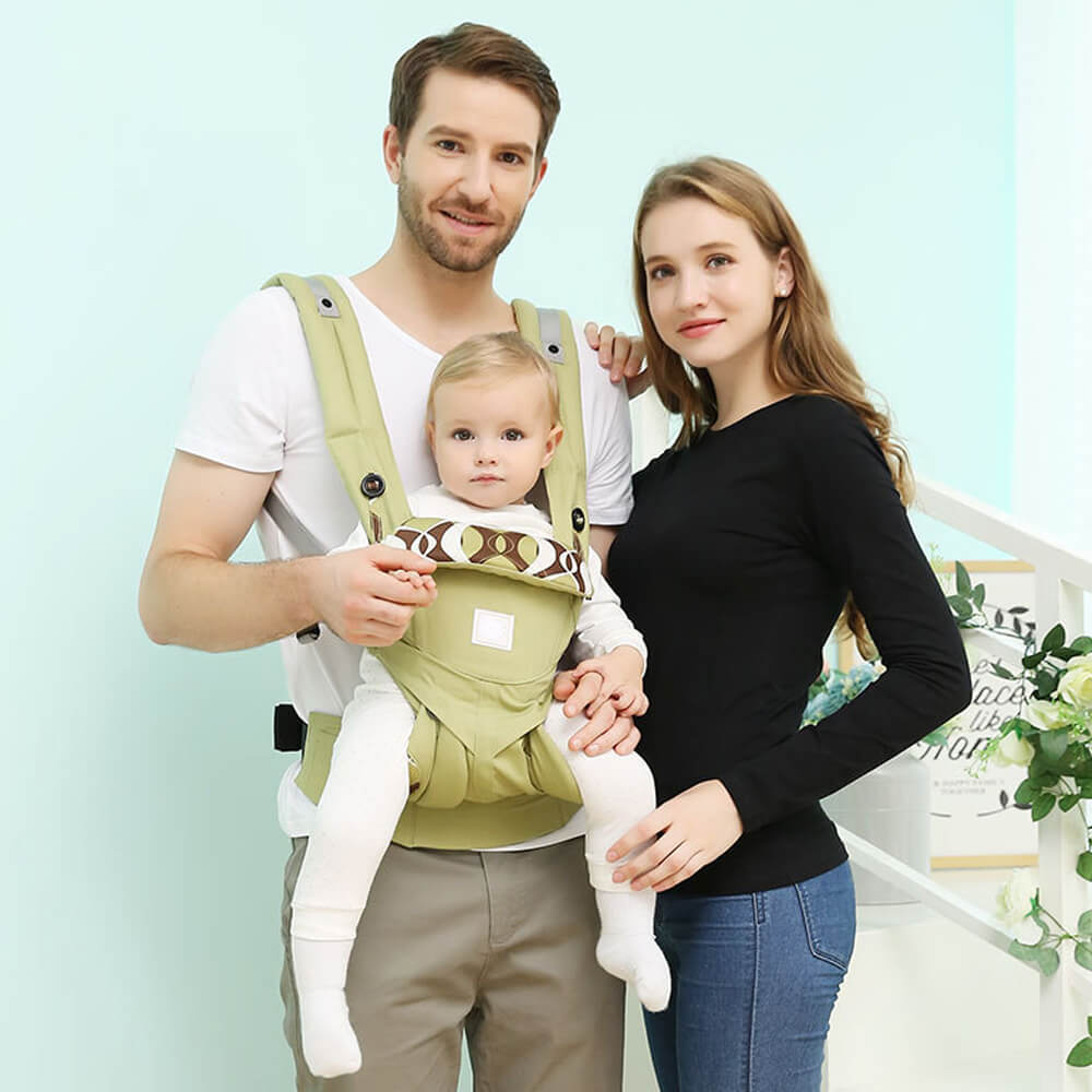 Babelio ergonomic baby carrier sling in pastel room, father carrying baby, mother beside