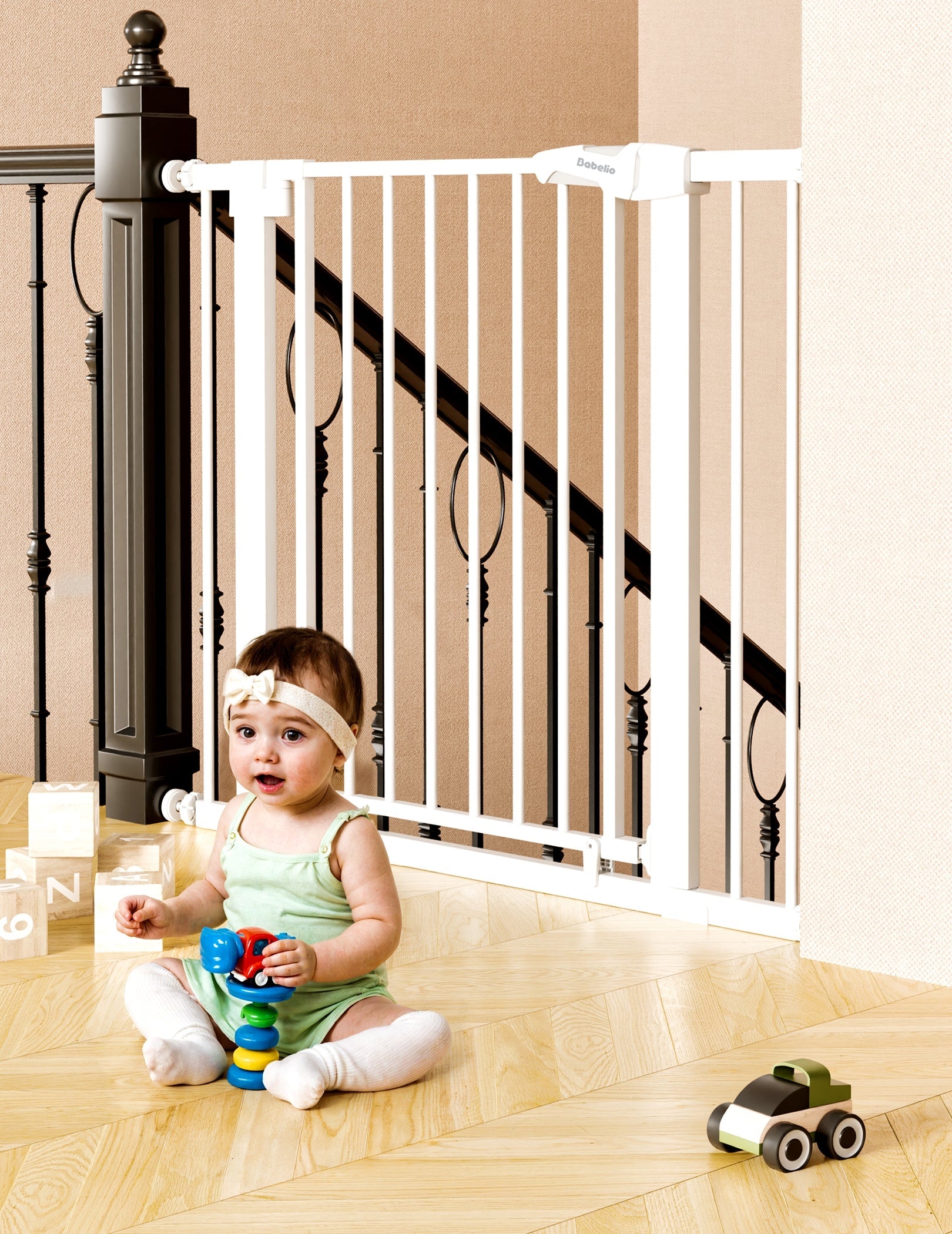 Babelio baby safety gate installed by stairs in living room with baby playing on floor