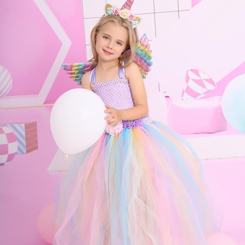 Babelio child in unicorn dress with pastel tulle skirt, holding balloon in a pink playroom