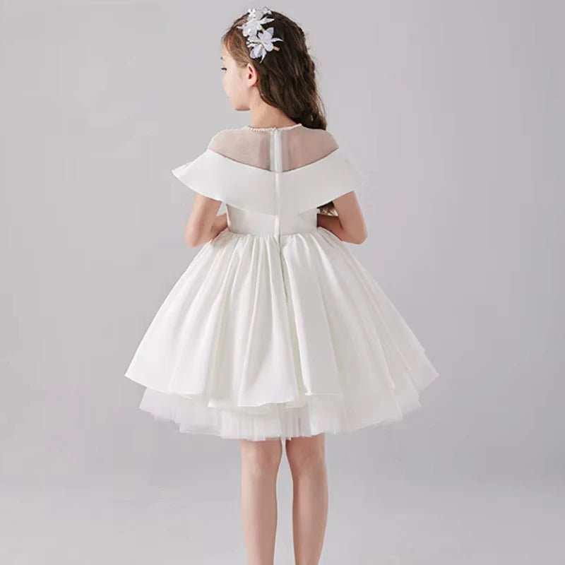 Babelio flower girl in white formal dress with floral hairpiece, studio background