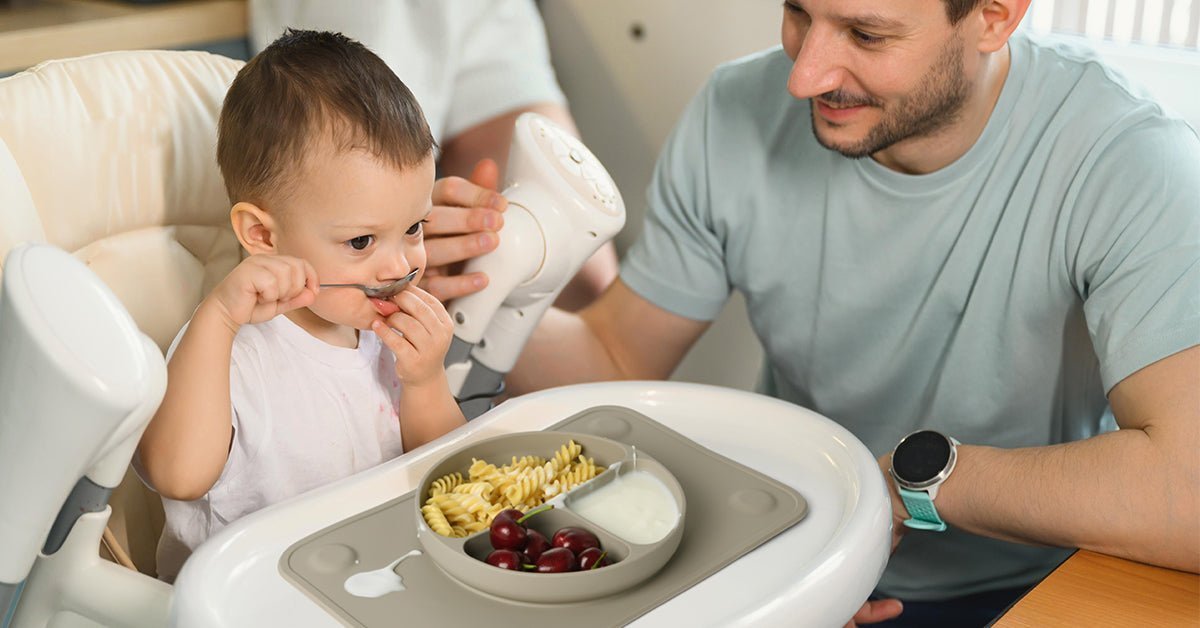 Father feeding baby in kitchen high chair, using Babelio baby safety products
