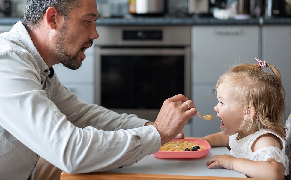 Parent feeding toddler healthy meal at kitchen table, perfect for modern family safety focus