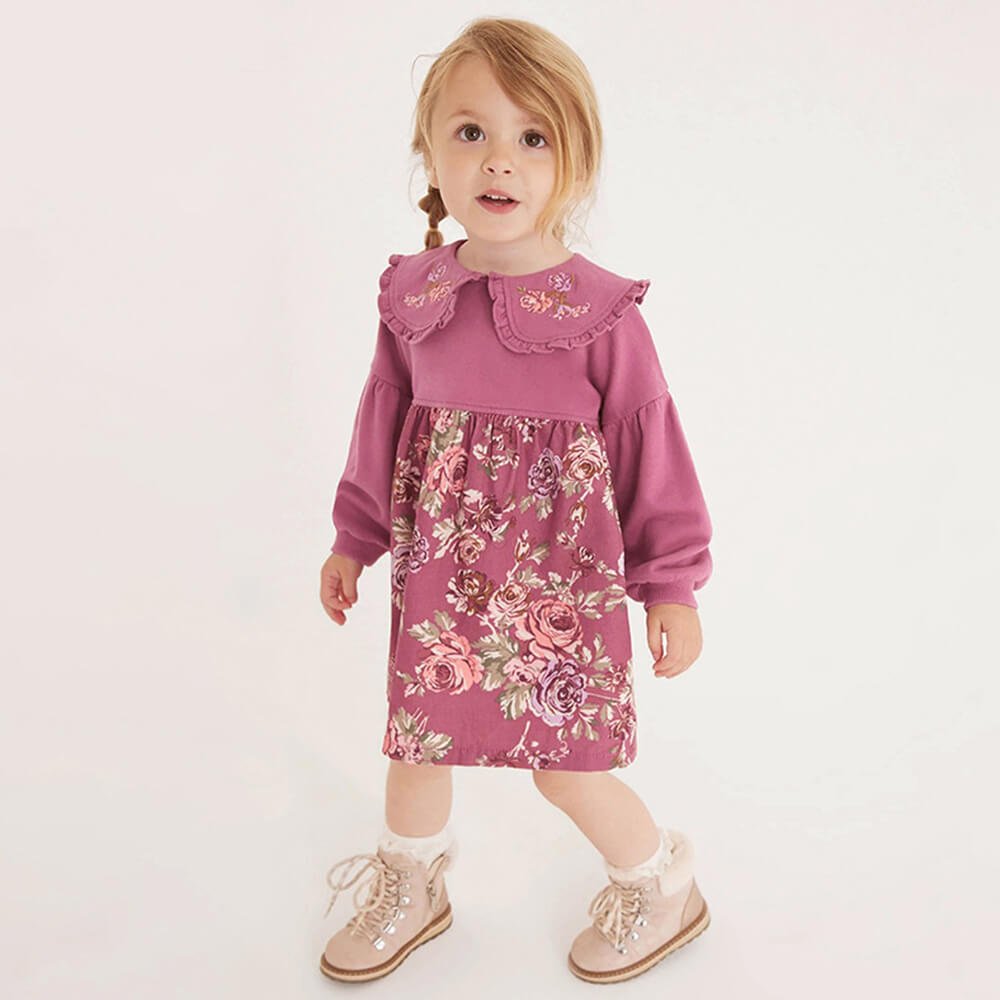 Young girl in floral pink dress and boots, standing indoors, babeliobaby fashion.