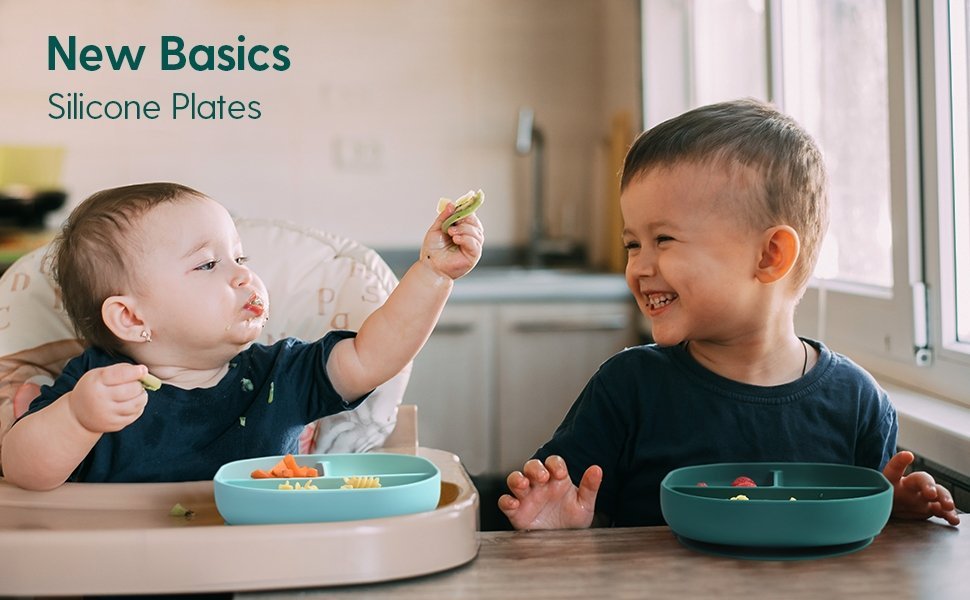 Smiling toddlers eating with divided silicone plates in a bright kitchen, Babelio baby products