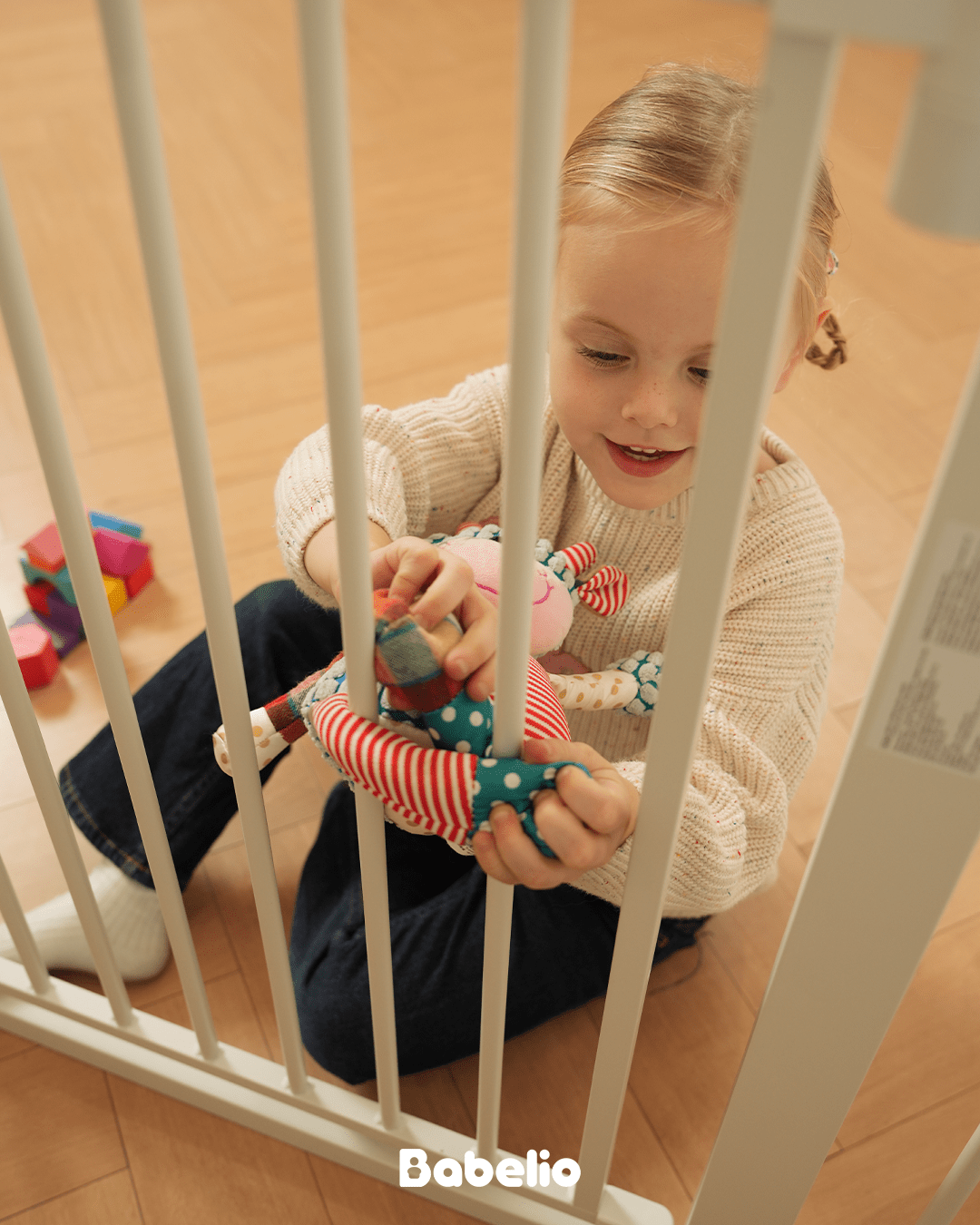 Babelio baby safety gate in a nursery with child playing on wood floor