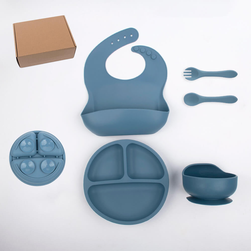 Blue silicone baby feeding set with bib, plates, bowl, utensils, and box on white background