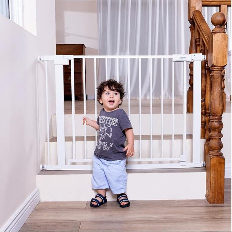 Child standing next to a baby gate in a home setting##Color_White