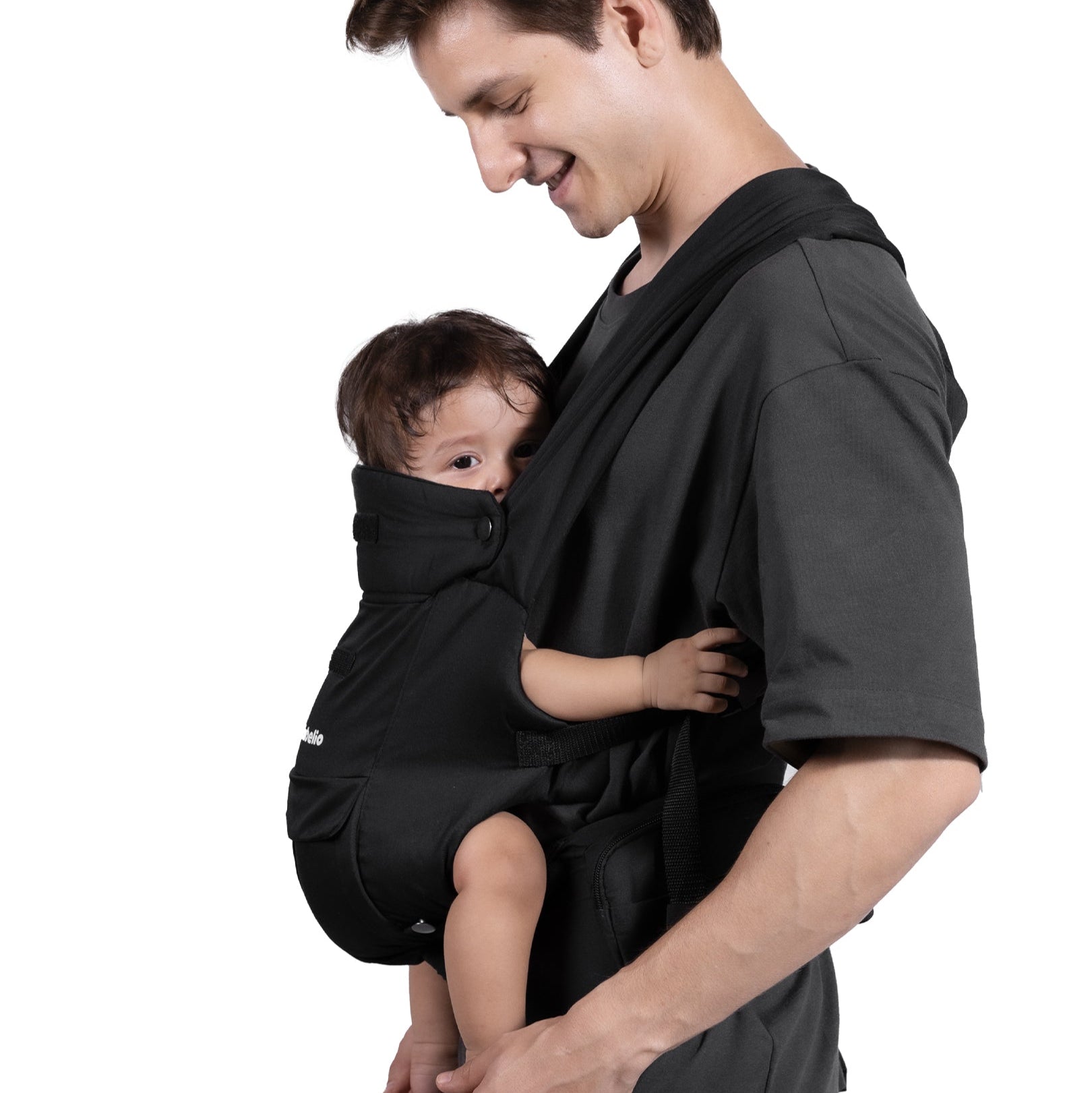 Man holding a baby in a black carrier against a white background