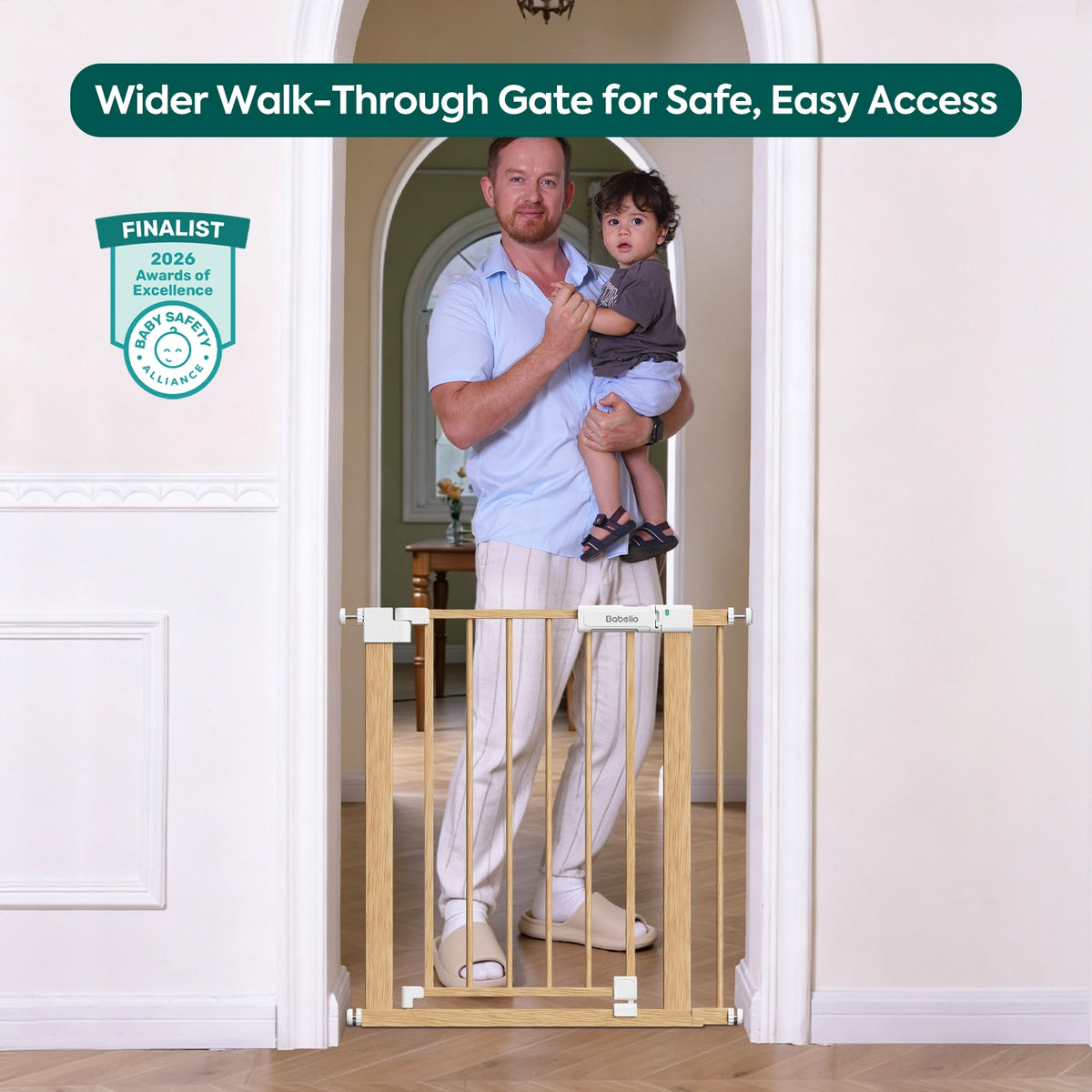 A light natural wood wider walk-through baby gate installed across a doorway, with a man holding a child standing behind it. The image includes marketing text at the top and a finalist badge on the left.#Color_Light Wood Pattern