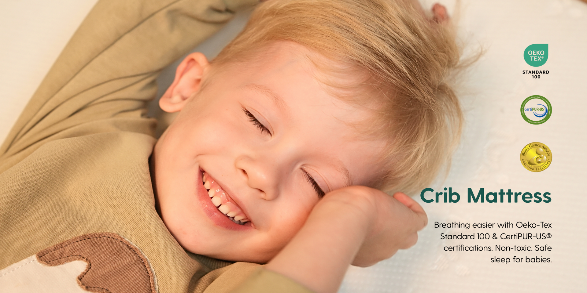 toddler lying on a Babelio crib mattress with certification logos in the corner