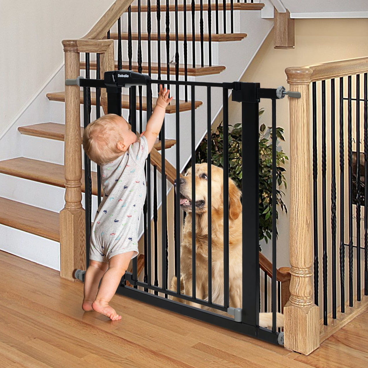 Child reaching out to a dog behind a black baby gate at the top of a wooden staircase.
