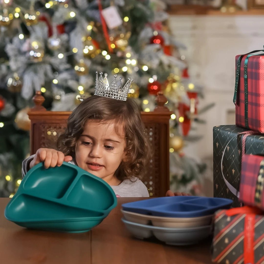 Toddler with Babelio baby suction plates in festive dining room by Christmas tree