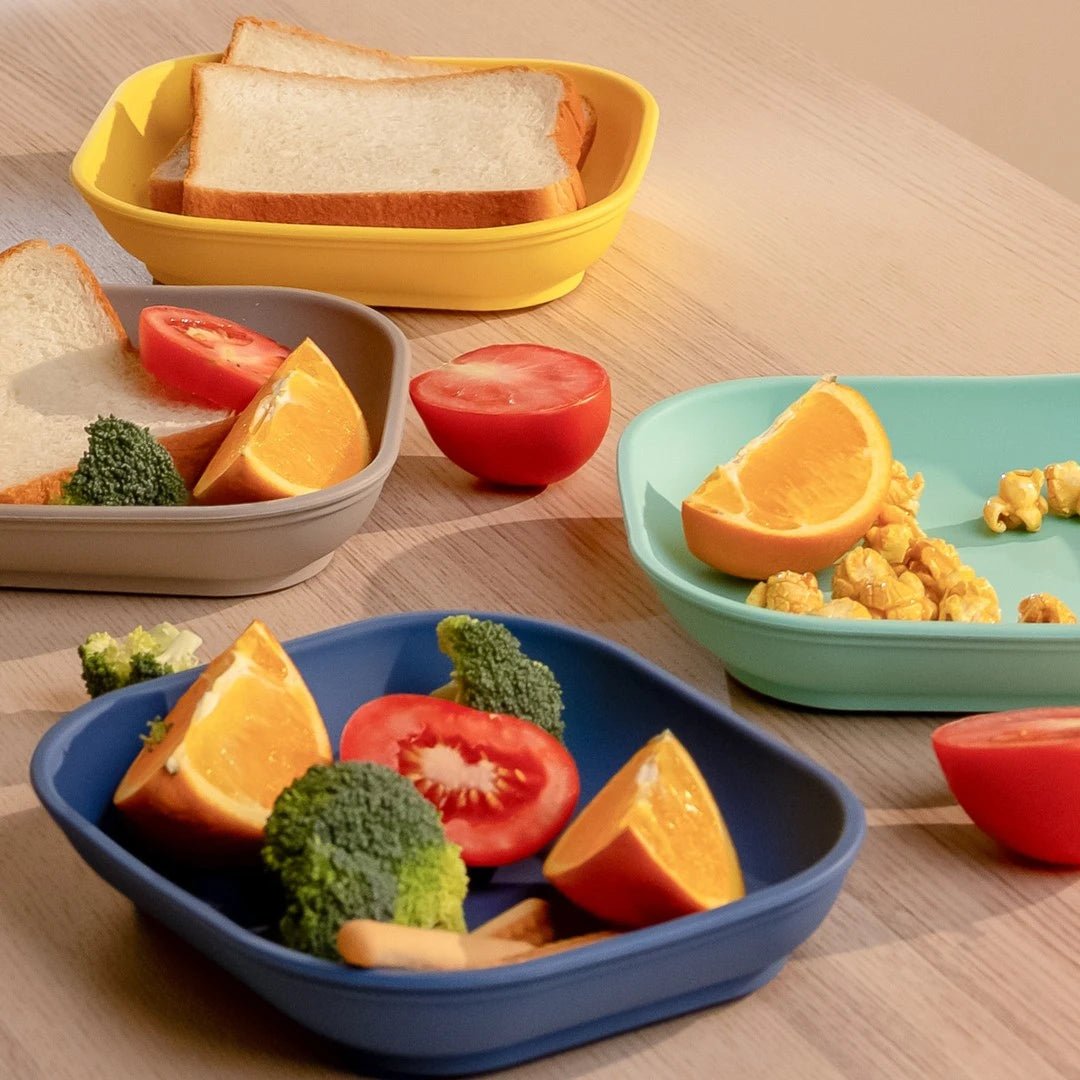 Babelio colorful plates with bread, oranges, tomato, broccoli, and snacks on a kitchen table