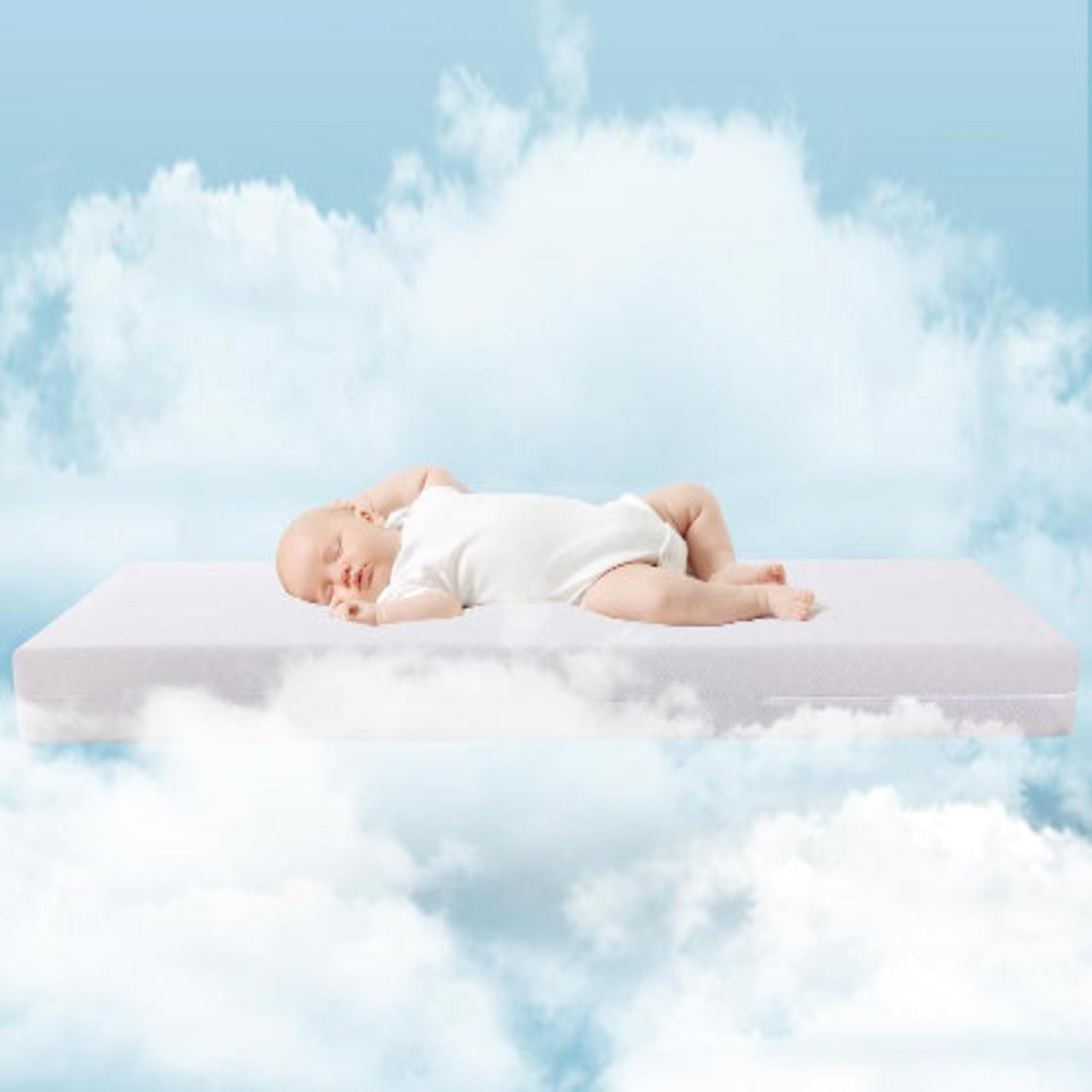 Baby lying on a Babelio crib mattress floating in the clouds with a blue sky background