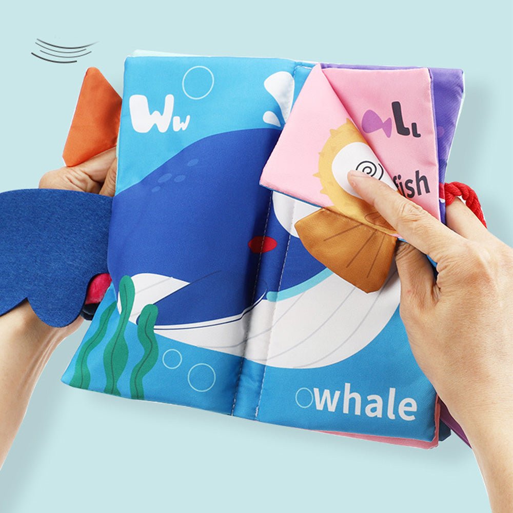 Babelio soft fabric baby book with whale illustration, hands turning interactive pages