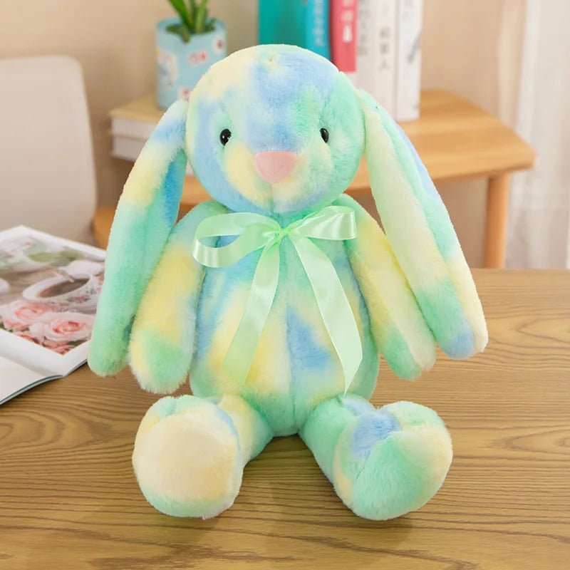 Babelio pastel plush bunny toy with green ribbon on a wooden table in a nursery setting