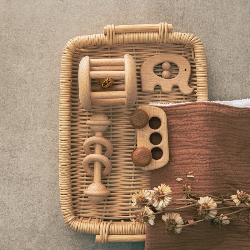 Babelio wooden baby toys in a basket on a nursery surface with brown cloth and flowers
