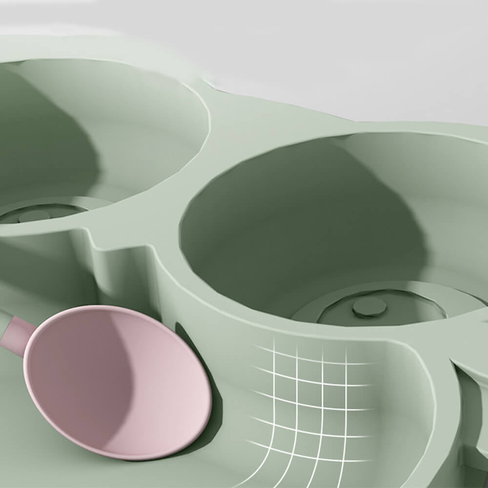 Babelio silicone divided toddler plate in sage green with pink spoon, close-up, kitchen setting