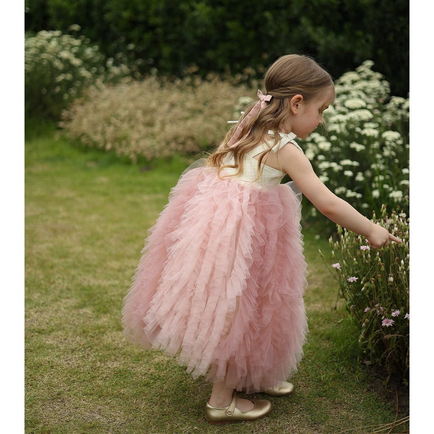 Little girl in a pink tulle dress picking flowers in a garden, Babelio
