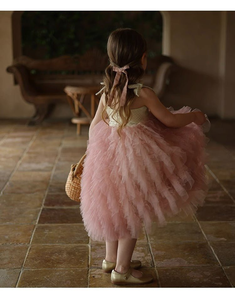 Young girl in pink tulle dress on tile floor, not featuring Babelio baby safety product.