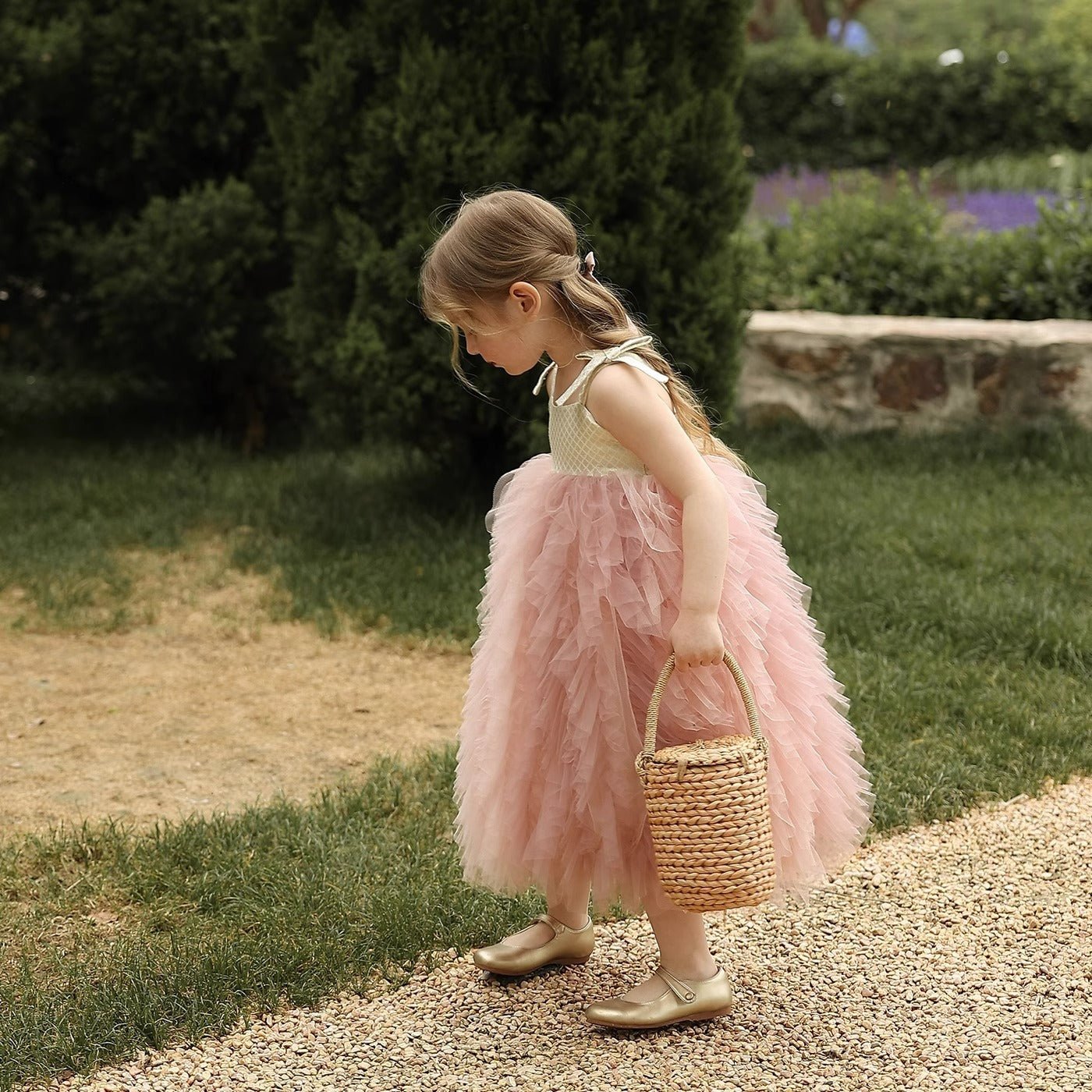 Young girl in pink dress holding woven basket outdoors, not a Babelio baby safety product