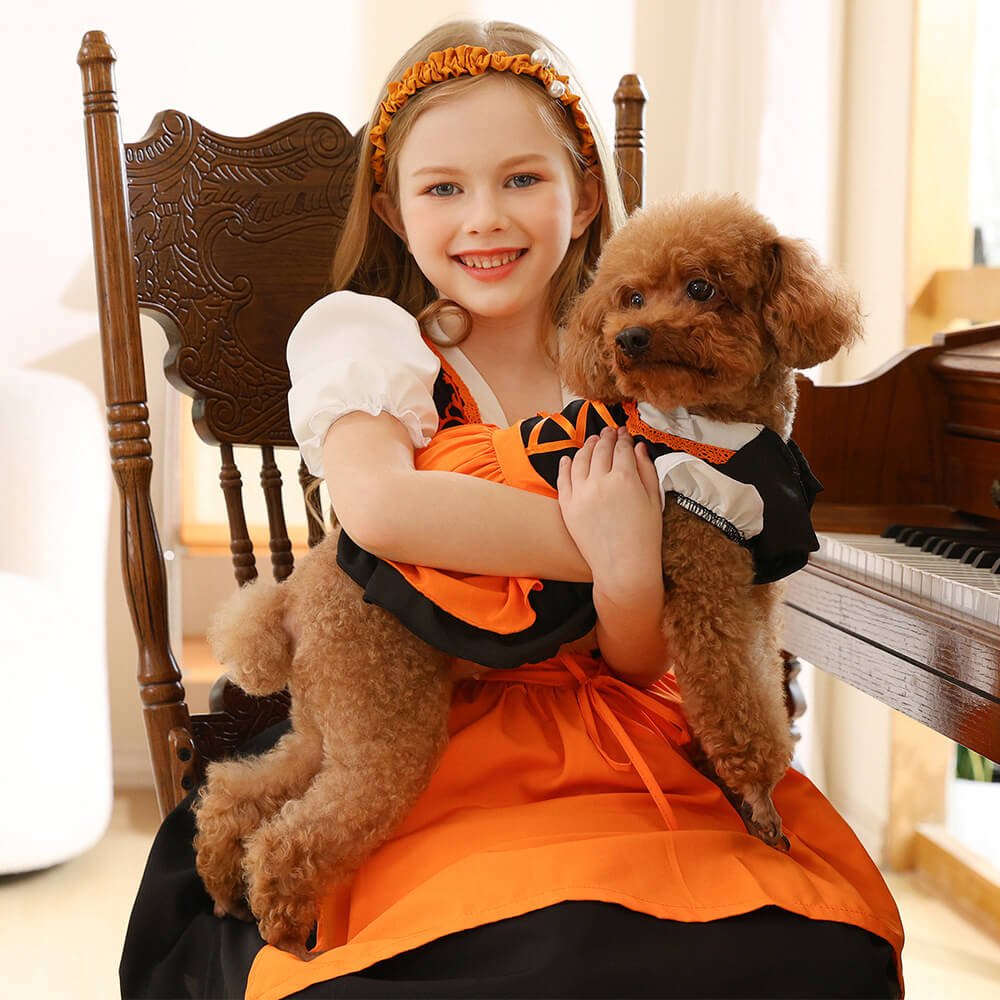 Smiling girl in orange dress and headband holding dog in matching outfit, Babelio living room