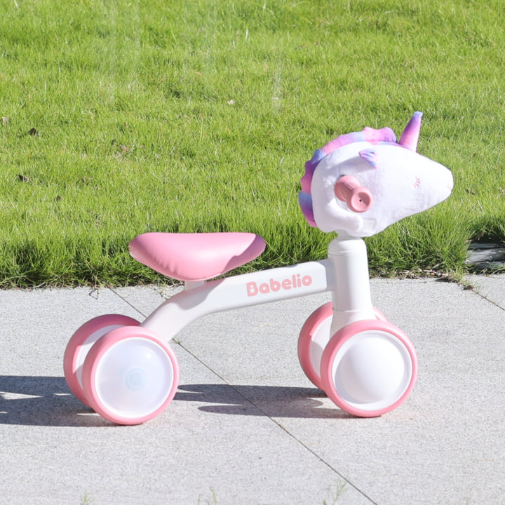 Pink and white toddler balance bike for 1–3 year old girls, featuring a cute unicorn head and LED glowing wheels, perfect for outdoor riding fun from the Magic Ride series by Babelio.